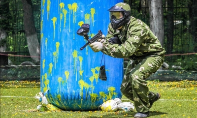 Person playing paintball holding gun in with blue bag in background