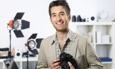 Man in beige suit holding black camera in photo studio