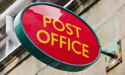 Red post office sign sticking out of beige wall