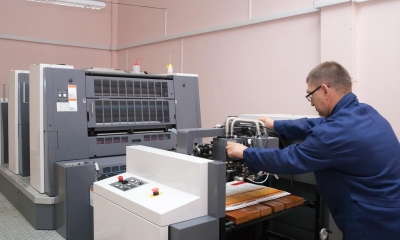 Man in blue boiler suit operating large printer