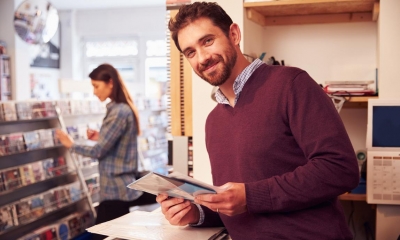 Man in brown sweater holding record with woman in background looking for records