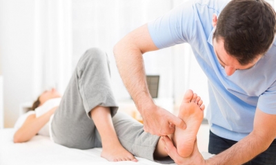 Customer lying on bench receiving foot massage from reflexologist
