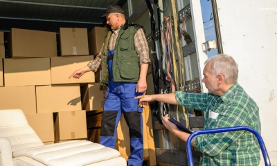 Two men unloading cardboard boxes from the back of a lorry