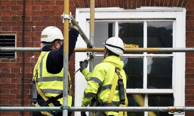 Scaffolders in high-visibility jackets working by a window