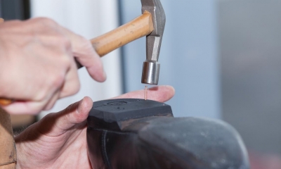 Person hammering nail into the heel of a black shoe