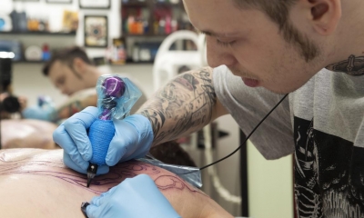 Man with sideburns giving customer a tattoo in a studio
