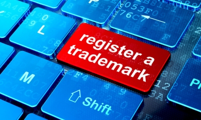 Blue computer keyboard with register a trademark written on a red key