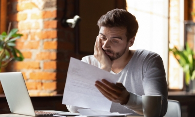 A stressed man reads a debt collection letter and worries about his legal rights.