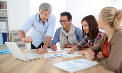 Marketing and selling Marketing team grouped around laptop and printouts