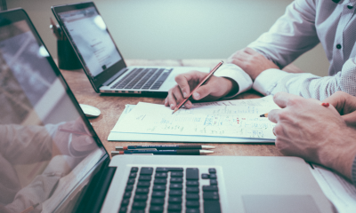 Two people at a desk, working on a paper document