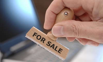 Selling your business Hand holding rubber stamp saying For Sale