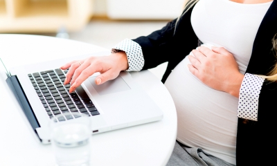 A pregnant employee works at her laptop