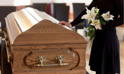 Woman at funeral holding flowers and touching coffin