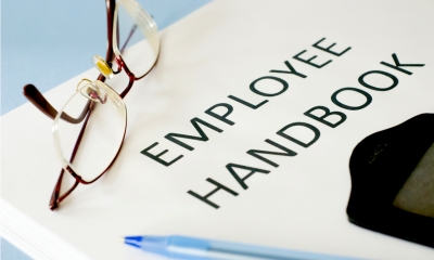 Pair of glasses rest ing on a piece of paper with Employee Handbook written on it