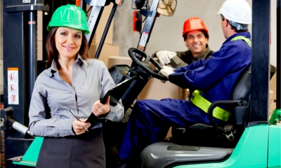 A female supervisor and delivery drivers in a warehouse wearing the correct safety gear.