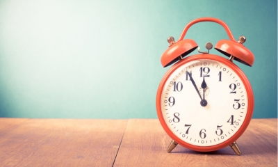 Retro red alarm clock with five minutes to twelve o'clock