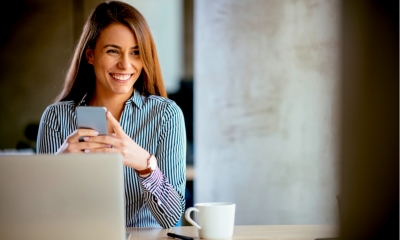 Business woman texting on the phone and working on laptop Business woman texting on the phone and working on laptop