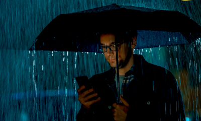 A man shelters under an umbrella in the pouring rain