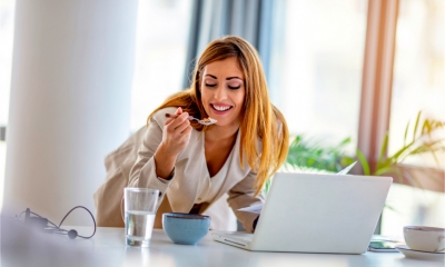 An attractive women eats breakfast whilst on a Zoom call