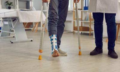 Male patient with a broken leg walking with crutches
