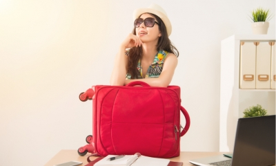 Cheerful office worker with luggage and sunglasses ready for long vacation holiday.