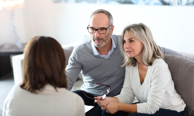 Claiming an inheritance Older couple sit together on a sofa chatting with a woman