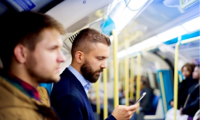 A businessman looks at his smart phone during a long commute
