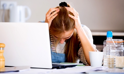 Woman holding her head in her hands next to a laptop after claiming constructive dismissal