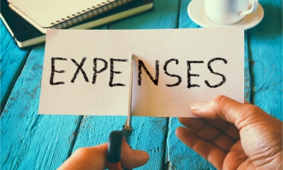 A man uses scissors to cut a card with the work expenses written on it in half.