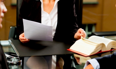 Female divorce lawyer in a suit sat at a desk flicking through pages of a book