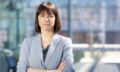 Close up portrait of a serious business woman in gray suit standing in the city