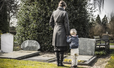 Family bereavement Woman and child stand together looking at a gravestone