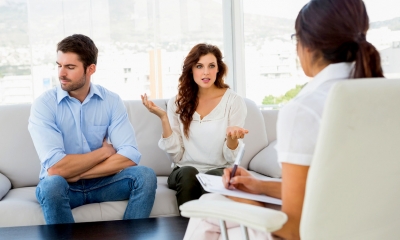 Couple sat on a sofa receiving family mediation from a female mediator