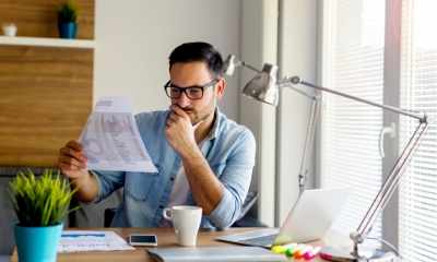 Man in glasses looking at a piece of paper with various sets of data on them