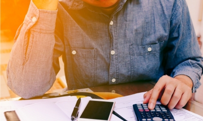 Person in a blue shirt using a calculator to work out the cost of a funeral