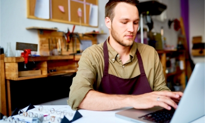 A small business owner manages customer records in a database on his laptop.