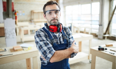 A man stood cross armed in a warehouse wearing protective goggles