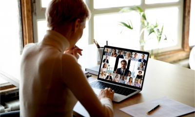 Rear view of a woman's head as she takes part in a groupchat with colleagues.