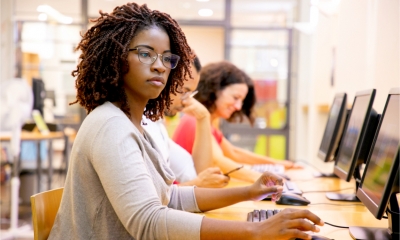 A row of employees work on computers in a modern office.