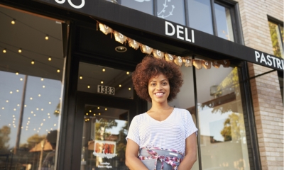 Black female business owner standing outside cafe shopfront