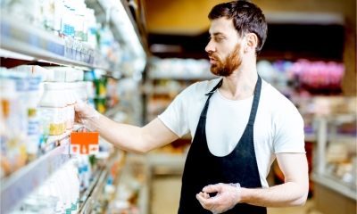 A male shopworker restocks the refrigerators in a supermarket