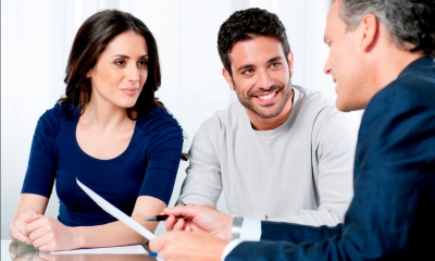 Young couple sitting together looking at a document being shown by an older man