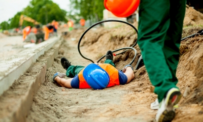 Person in high-vis lying down by the road after having an accident at work