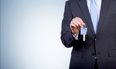 Man in suit holding a set of keys to a property