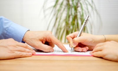  Mains masculines pointant vers l'endroit où la main féminine tient un crayon pour signer le document