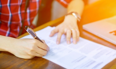 Person in a red shirt writing on a divorce form using a black pen