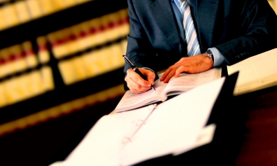 Male divorce lawyer in a suit writing into a booklet with a folder in front of him