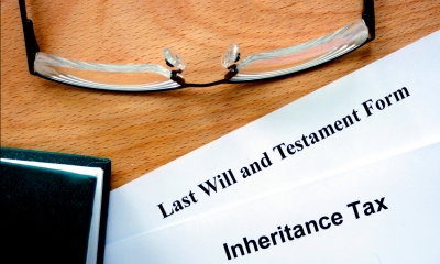 Documents headed last will and testament and inheritance tax on a table next to a pair of glasses