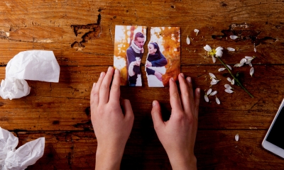 Person holding two seperate parts of a picture of a couple