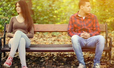 A man and woman sit at opposite ends of a bench